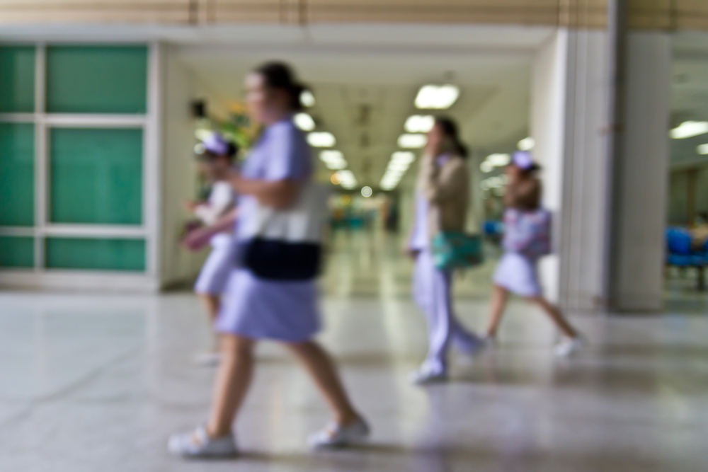 Blurred nurses walking through hospital corridor