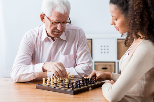 young woman playing chess with elderly man