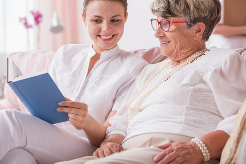 younger woman reading to elderly woman